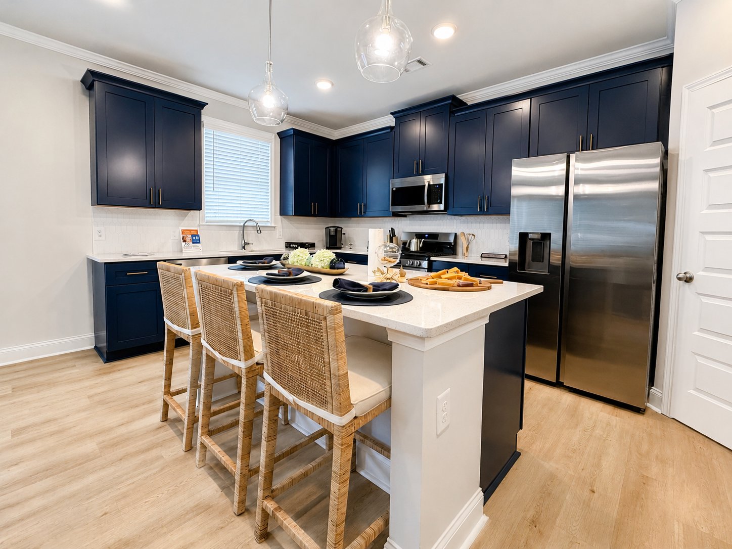 Kitchen with navy blue cabinets, quartz island, and rattan bar stools